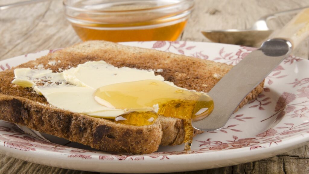 Miele d'acacia BIO spalmato su una fetta di pane e burro. 
